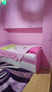 a pink bedroom with a bed and a purple wall at Apartman Batuta in Budva