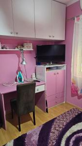 Zimmer mit einem Schreibtisch und einer rosa Wand in der Unterkunft Apartman Batuta in Budva