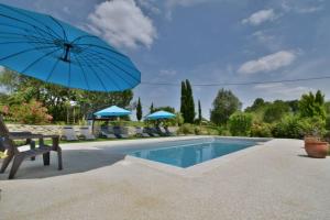 een zwembad met een blauwe parasol en stoelen en een tafel bij Chambre d'hôtes La Détente - Domaine la Rose des vents in Castelnau-sur-lʼAuvignon