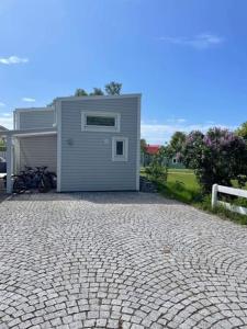 a small house with a brick driveway next to a building at Nybyggt gästhus nära havet och Göteborg in Kullavik