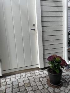 a potted plant sitting in front of a door at Nybyggt gästhus nära havet och Göteborg in Kullavik