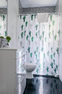 a bathroom with a toilet and a shower curtain with cactus at Playa 4 a solo 3 min - Apartamento en Castelldefels in Castelldefels