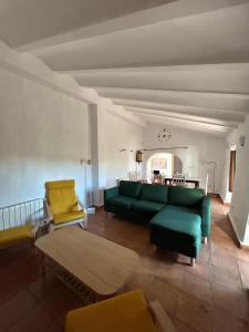 ein Wohnzimmer mit einer grünen Couch und gelben Stühlen in der Unterkunft Rancho Burruelo in Algodonales
