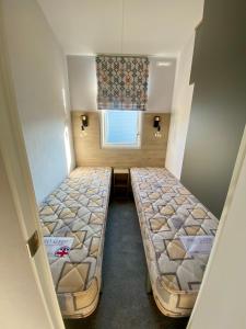 um pequeno quarto com 2 camas e uma janela em Hafan Y Môr Caravan - Pwllheli em Chwilog