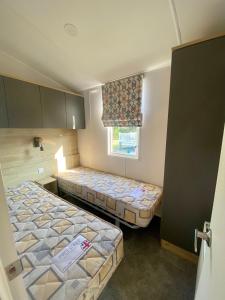 two beds in a small room with a window at Hafan Y Môr Caravan - Pwllheli in Chwilog