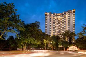 un edificio alto con árboles frente a una calle en Shangri-La Eros New Delhi, en Nueva Delhi