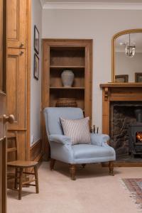 uma sala de estar com uma cadeira azul e uma lareira em Lonach Coaching Inn 