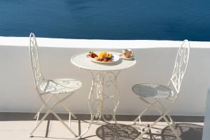 a table with a plate of food and two chairs at Bligos Villas in Oia