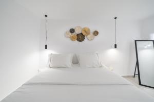 a white bedroom with a bed and a clock on the wall at Bligos Villas in Oia