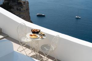 a table and chairs on a balcony with a view of the water at Bligos Villas in Oia