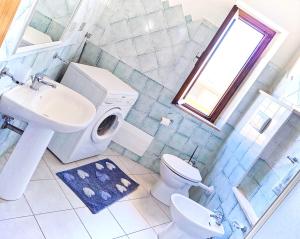bagno con lavandino, servizi igienici e finestra di Appartamento Neruda a Cala Gonone