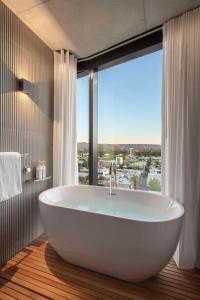 Vibe Hotel Adelaide في أديلايد: حوض استحمام في حمام مع نافذة كبيرة