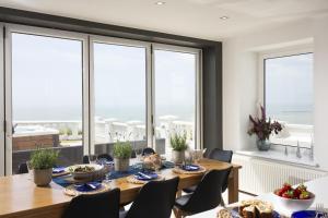 jadalnia ze stołem, krzesłami i oknami w obiekcie Abbots Cliff House by Bloom Stays w mieście Hougham