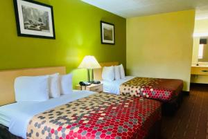 two beds in a hotel room with green walls at Super 8 by Wyndham Gloucester in Gloucester City