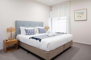 een slaapkamer met een groot bed met blauwe en witte kussens bij First Light Mooloolaba, Ascend Hotel Collection in Mooloolaba