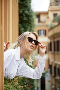 a woman wearing sunglasses is leaning against a building at NAMAN HOTELLERIE - Margutta in Rome