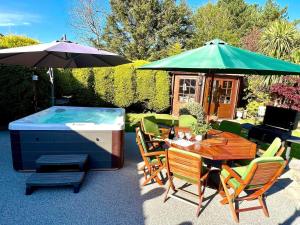 a hot tub and a table with chairs and an umbrella at Fairways Villa Newcastle in Newcastle