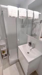 uma casa de banho branca com um lavatório e um chuveiro em 2023 Bruno - wifi and parking available em Portorož