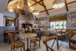 un restaurante con mesas y sillas de madera y una pared de ladrillo en The Craster Arms Hotel in Beadnell en Beadnell