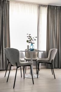 a dining room table and chairs in front of a window at Wiejska Glamour Apartment in Warsaw