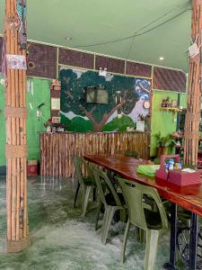a dining room with wooden tables and green chairs at Khao Sok Green Mountain View in Khao Sok