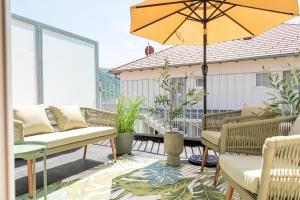 eine Terrasse mit Stühlen und einem Sonnenschirm auf dem Balkon in der Unterkunft Spitz Deluxe in Sankt Johann im Mauerthale