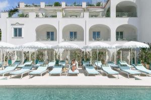 une femme assise sur une chaise à côté d'une piscine dans l'établissement Hotel La Palma Capri, an Oetker Collection Hotel, à Capri