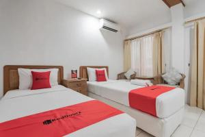 two beds in a room with red and white at RedDoorz At Arwiga Hotel in Bandung