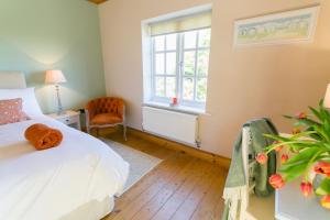 a bedroom with a bed and a window and a chair at Glan Gors Felin in Llanrhyddlad