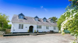 a white house with a black roof at Glan Gors Felin in Llanrhyddlad