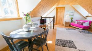 a dining room with a table and a pink couch at Glan Gors Felin in Llanrhyddlad