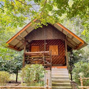 a small wooden cabin with stairs in a forest at Khao Sok Green Mountain View in Khao Sok National Park
