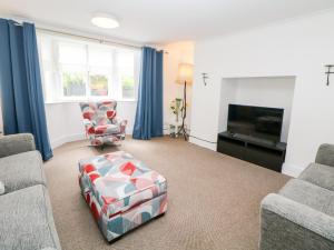 a living room with a couch and a chair and a tv at Garden Apartment in Buxton