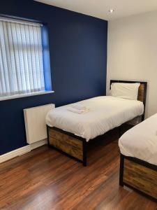 um quarto com 2 camas e uma parede azul em Work-Play Stylish, Speedwell Apartment, Free Parking em Bristol
