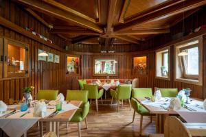 a dining room with tables and green chairs at Ortners Eschenhof - Alpine Slowness in Bad Kleinkirchheim