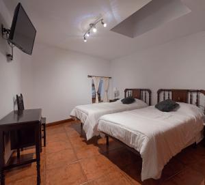 Cette chambre dispose de 2 lits, d'une télévision et d'un piano. dans l'établissement Alojamiento Rural Casa Ezkerra, 