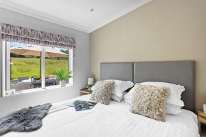 a bedroom with a large white bed with a window at Cherry Lodge, 14 Roadford Lake Lodges in Lifton