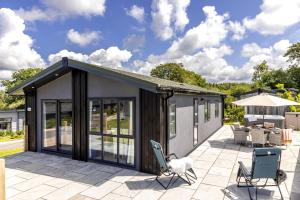 a modular house with windows and chairs on a patio at Cherry Lodge, 14 Roadford Lake Lodges in Lifton