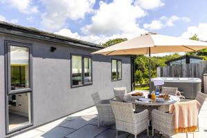 a patio with a table with an umbrella at Cherry Lodge, 14 Roadford Lake Lodges in Lifton