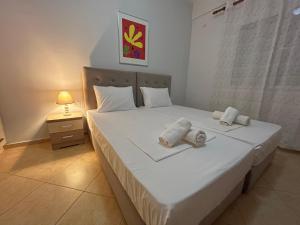 ein Schlafzimmer mit einem weißen Bett und Handtüchern darauf in der Unterkunft Miranda's Apartments & Rooms in Sarandë