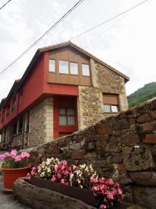 a house with flowers in front of a stone wall at Apartamentos Remoña 1 in Espinama