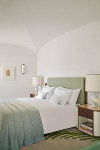 a bedroom with a large white bed and two tables at Hotel La Palma Capri, an Oetker Collection Hotel in Capri