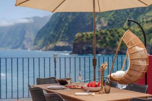 a table with an umbrella and a view of the water at Holiday home by the sea Pipas do Avô - Seixal in Porto Moniz