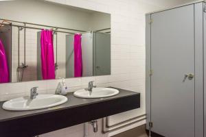 a bathroom with two sinks and pink showers at inBraga Hostel in Braga