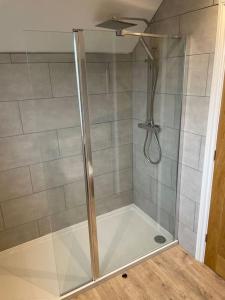 a shower with a glass door in a bathroom at Falabella Suite with amazing views of stud farm. in Great Driffield