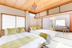 two beds in a room with wooden ceilings at Chikyuutabikazoku　Kintetsu-Nara Ekimae in Nara
