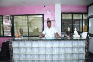 Een man achter een toonbank in een restaurant. bij Hotel Kewal INN in Jālgaon