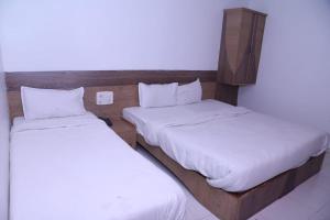 2 Betten in einem kleinen Zimmer mit weißer Bettwäsche in der Unterkunft Hotel Kewal INN in Jālgaon