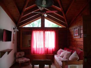 sala de estar con sofá y ventilador de techo en Cabañas de Colores en Los Reartes