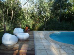 dos sillas blancas sentadas junto a una piscina en Cabañas de Colores en Los Reartes